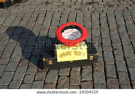 Asking for a contribution. Upturned hat on a musical instrument box with a sign saying Thank You
