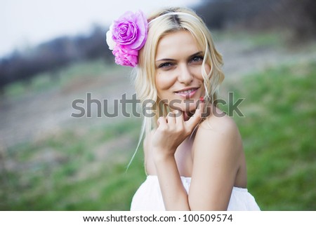 Portrait of beautiful young blond woman in white blouse at park holding her lips