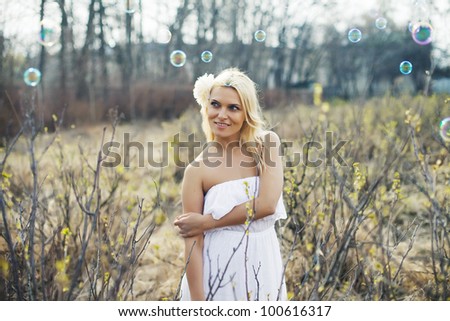 beautiful happy young woman in the park on a warm summer day with soap bubbles