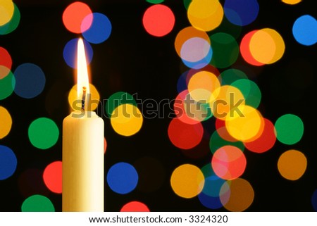 Candle with flame over colorful lights background