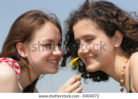 Two young beautiful girls face to face with dandelion