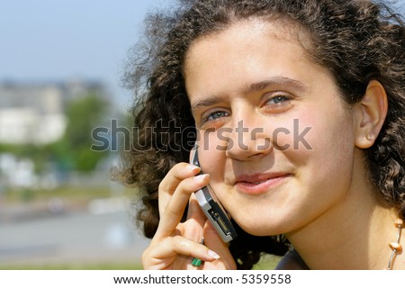 Young smiling girl with cell phone, city in the background is out of focus