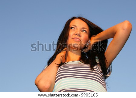 Young happy woman against blue sky at evening light