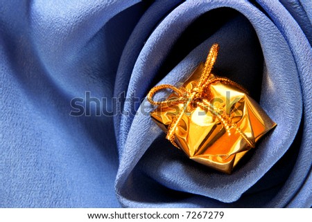 Expensive gift over blue silk background with folds