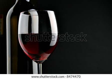 Bottle and glass over black background with space for your own text on right