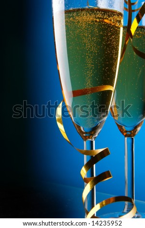 Couple glasses of champagne with gold streamer over blue background