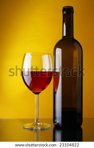 Wineglass and bottle of red wine over yellow background