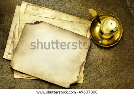 Old pages and candle on wooden table