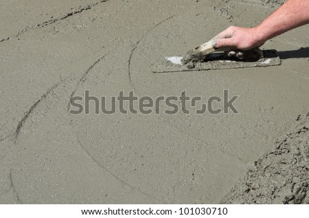 A mason hand finishes a newly poured concrete floor