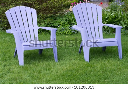 Two purple chairs sitting on a fresh green lawn
