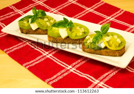 Fresh bruschetta with green heirloom tomatoes cheese and basil on red cloth