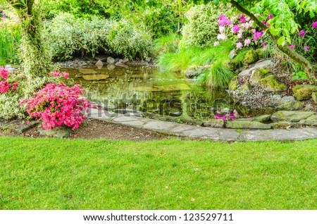 A garden scene with blooming azaleas and a fish pond