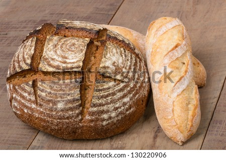 A loaf of fresh rye bread on a table with french baguette loaf