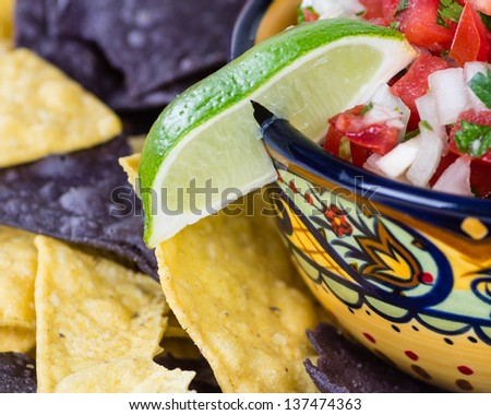 A fancy bowl with nacho corn chips and fresh onion tomato salsa