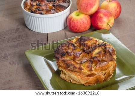 Apple bread pudding on green plate with apples and bowl