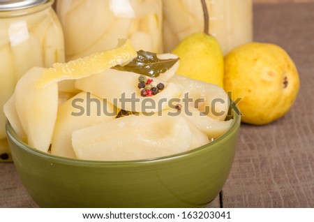 A bowl of fresh canned spiced pears with jars of pears