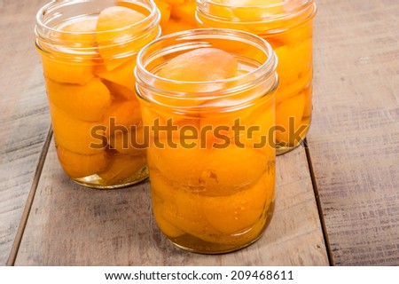 Small mason jars of sliced fresh yellow peaches on a wooden table