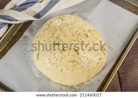 Artisan rosemary bread with egg wash rising on sheet pan