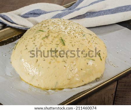 Artisan rosemary bread with egg wash rising on sheet pan