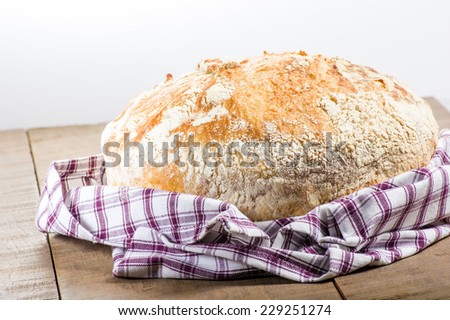 A cloth wrapped fresh baked loaf of bread