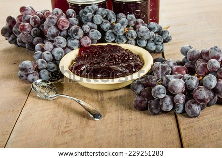 Bowl of fresh grape jelly with grapes and jars