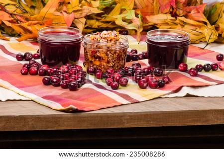 Jars of cranberry sauce with cranberries on a wooden table