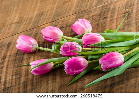 Fresh cut bundle of pink tulips on a wooden table