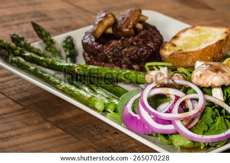 Steak and spinach salad with onion rings and mushrooms