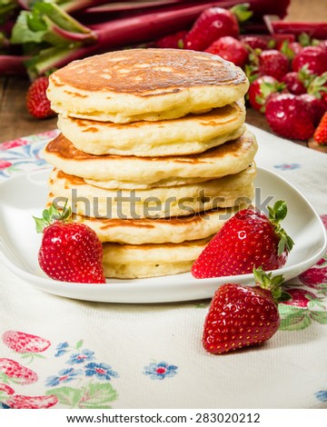Pancakes with strawberries on white plate stacked
