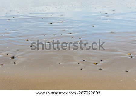 Pebbles in the sand cause patterns by moving water