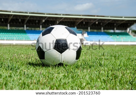 close up of black and white soccer on field with stadium background