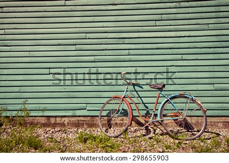 Abandoned bike leaning against a green wall.