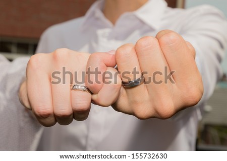 Couple linking their hands with little fingers showing their wedding rings