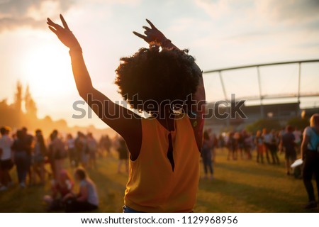 Young African American woman dancing at summer holi festival, back view