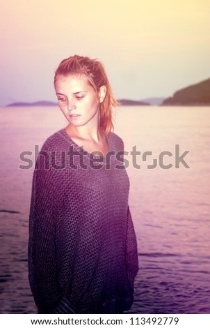 Beautiful woman in sweater comes in the sea in the evening, cross process