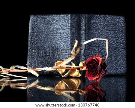 Old leather book cover wilted rose reflected in black surface