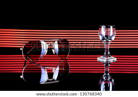 Glass of alcohol and sunglasses on disco background, summer party atmosphere