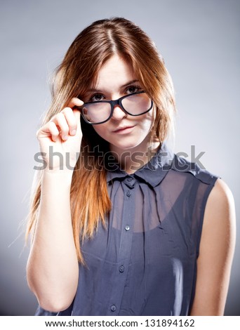 Strict serious young woman holding large nerd glasses