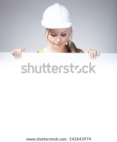 Young builder woman construction worker and empty poster