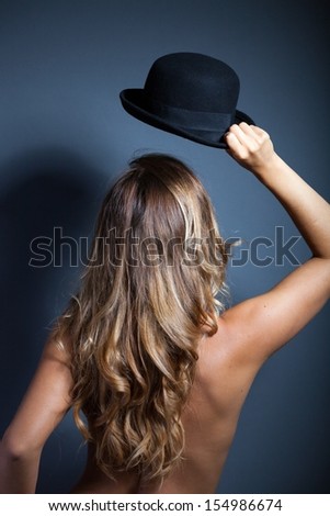 Naked woman standing back wears a hat on her head