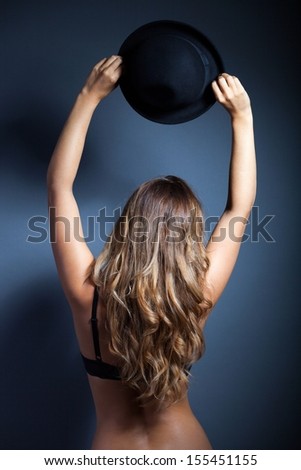 Sexy woman in lingerie holding her hat above head