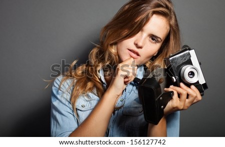 Thinking photographer woman holding old camera