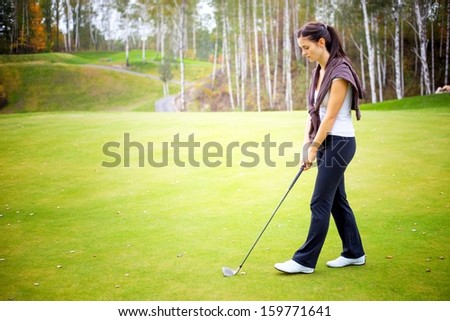 Young woman golf player training on green with club