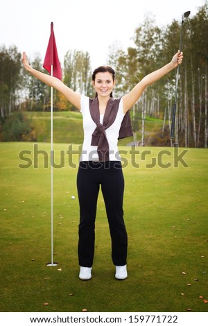 Overjoyed and smiling woman golf player in winner pose on green
