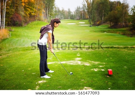 Young woman golf player on course preparing to golf swing, training and exercise