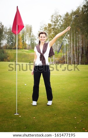 Happy and smiling woman golf player in winner pose on green