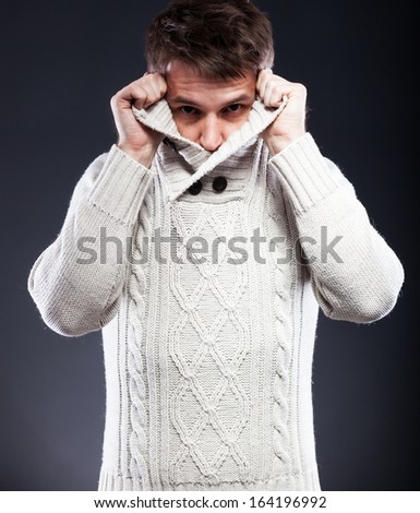 Young man in white sweater shivering from the cold