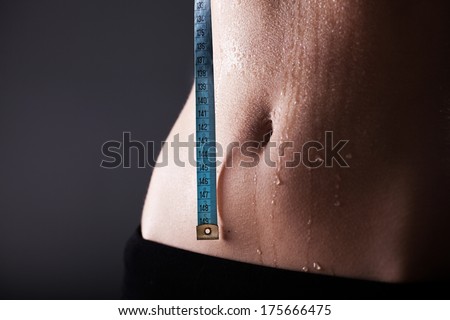 Fitness woman sweaty sporty belly after exercise with measuring tape, weight loss concept