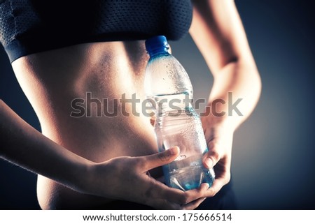 Sweaty fitness woman after training holding water bottle