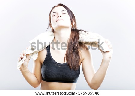 Tired young woman after fitness exercise wiping with towel